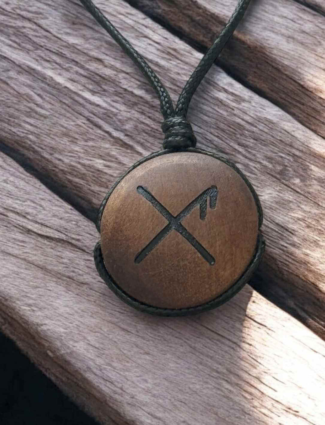 Binderune für Glück, rundes Holz-Amulett mit Rune, auf hellem Holz fotografiert