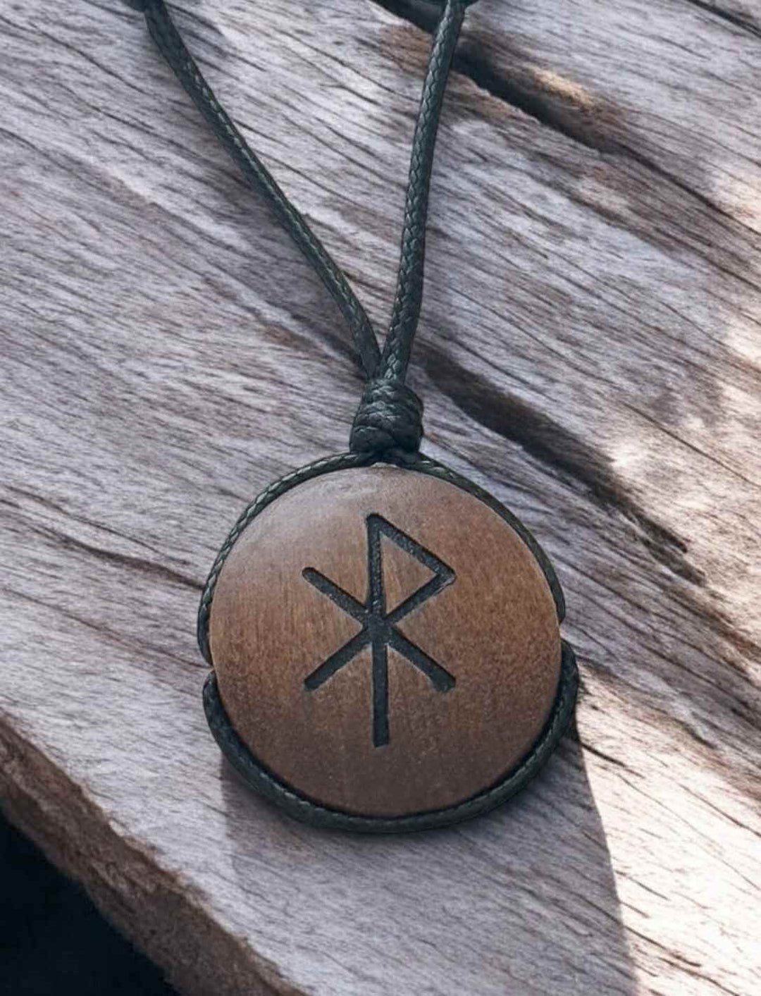 Binderune für Liebe, Holz-Amulett mit eingraviertem Symbol, Nahaufnahme auf Holz