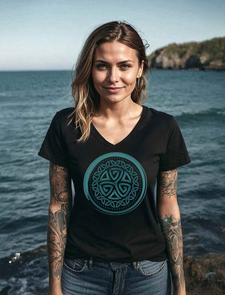 Model trägt das Aqua Triskele Damen V-Neck Shirt in Schwarz vor felsiger Küstenlandschaft