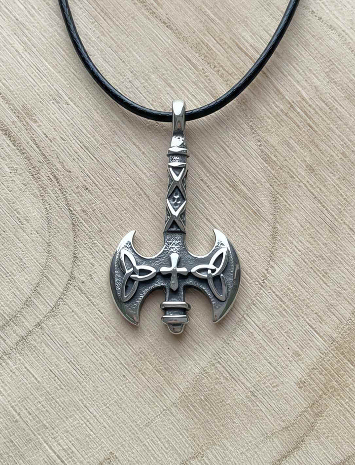 Detailaufnahme der „Axt des Sonnenkreuzes“ aus Edelstahl auf hellem Holzuntergrund an Lederkette 2mm Stärke.