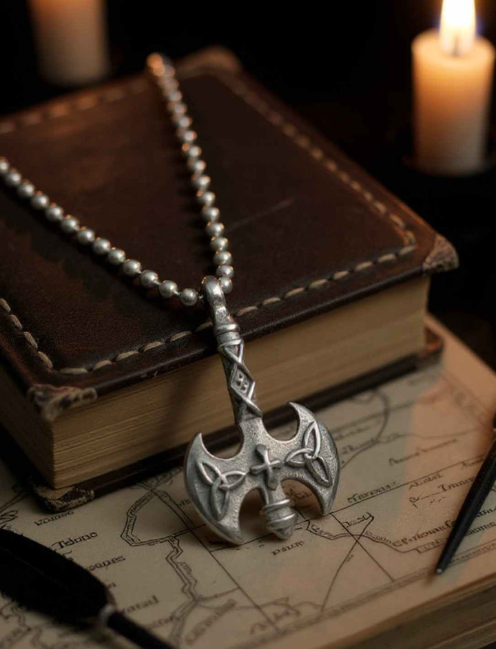 Edelstahl-Doppelaxt mit Sonnenkreuz-Motiv auf Kugelkette, dekorativ auf altem Buch platziert an Edelstahlkette silberfarben.