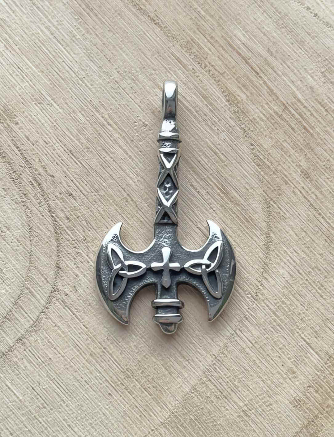 Edelstahl-Anhänger „Axt des Sonnenkreuzes“ an Lederband, fotografiert auf Holz.