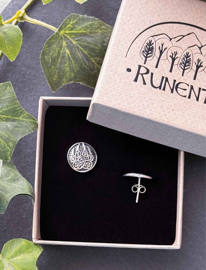 Silberner Ohrstecker Bärentatze mit keltischem Design in Runental-Schmuckbox, fotografiert auf steinernem Untergrund