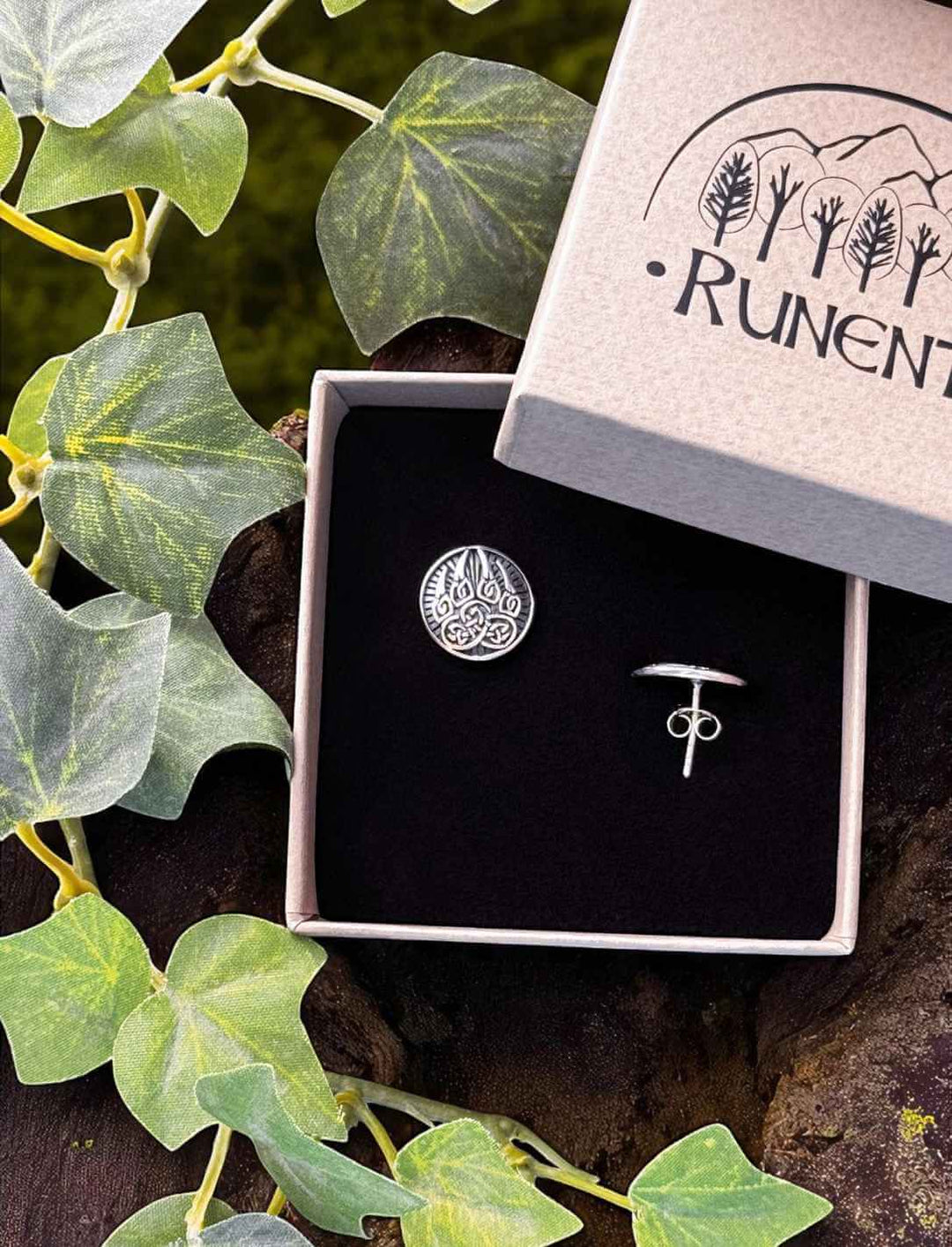Bärentatze des Druiden – silberner Ohrstecker mit keltischem Tatzenmotiv in Runental Geschenkbox auf Baumstumpf mit Efeu fotografiert.