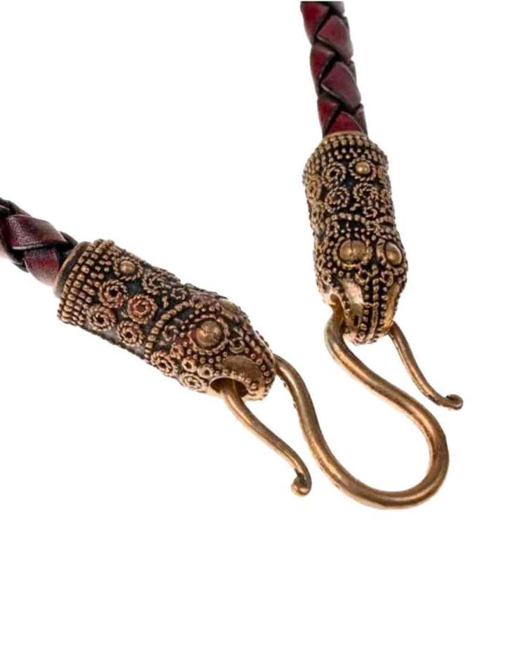 Braune Wikinger Lederkette mit bronzefarbenen Rabenkopf-Endkappen, eingefangen in natürlicher Umgebung.