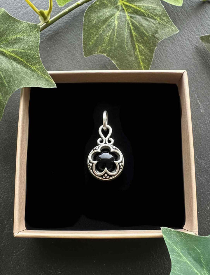 Onyx Frontansicht: Blüte von Gotland – Silberamulett mit schwarzem Onyx, inspiriert von nordischer Ornamentkunst in Runental Verpackung.