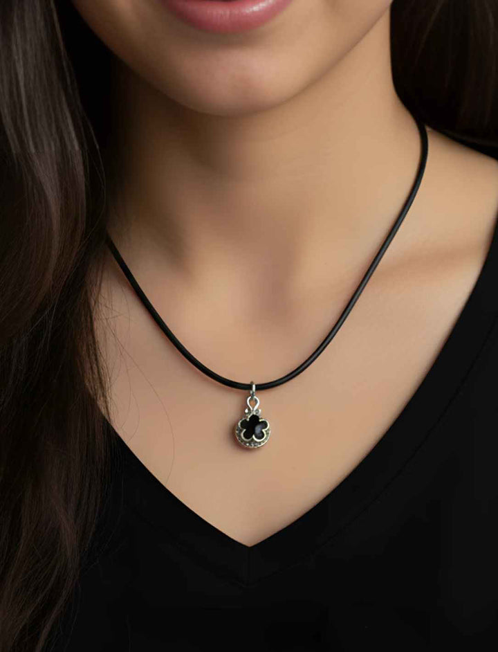 Silberanhänger Blüte von Gotland mit dunklem Onyx, filigrane Blütenornamente aus Sterling Silber an Lederkette, getragen von junger Frau.