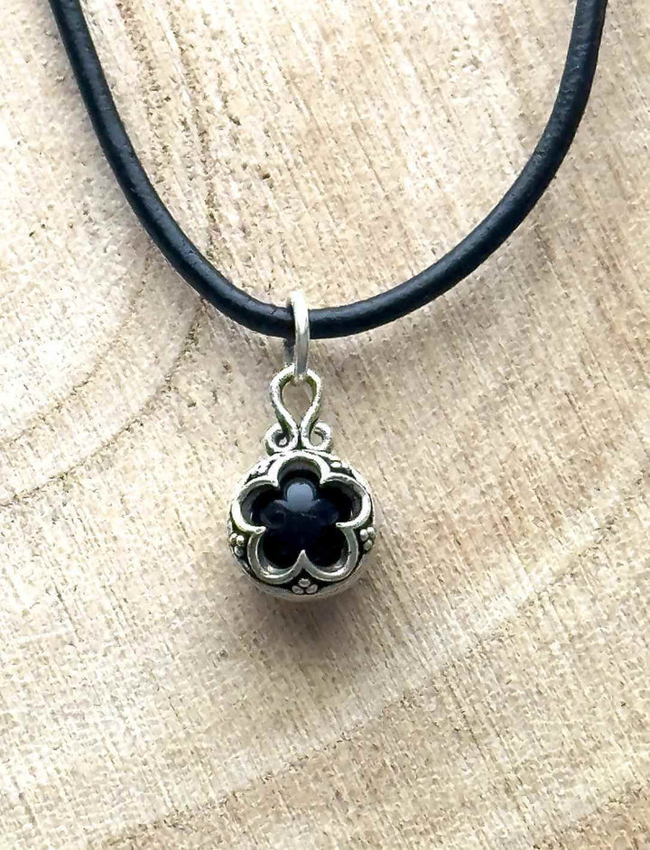Blüte von Gotland – Silberamulett mit Onyx in schwarz,  inspiriert von Gotland-Ornamenten auf hellem Tisch.
