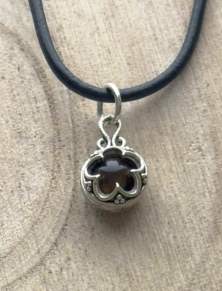 Blüte von Gotland – Silberanhänger mit dunkelbraunem Tigerauge auf heller Holzoberfläche an Lederband.