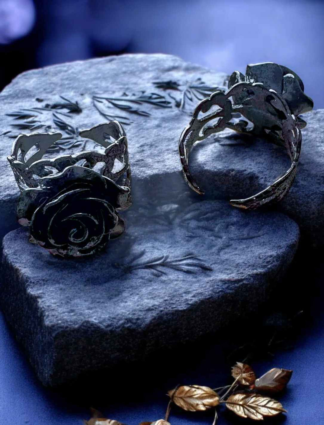 Zwei schwarze Rosenringe aus Edelstahl auf Herzstein – seitliche Ansicht mit detailreicher Ringschiene