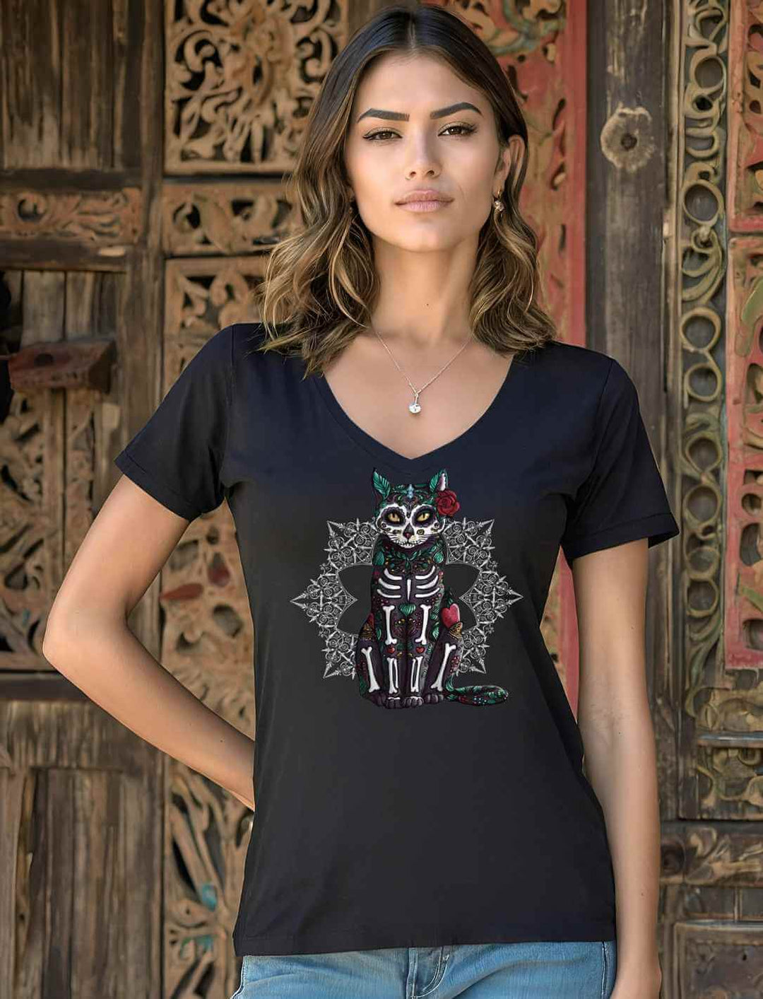 Junge Frau trĂ€gt das Catrina Felina Damen V-Neck Shirt in schwarz im Hintergrund eine Holzschnitt-TĂŒr