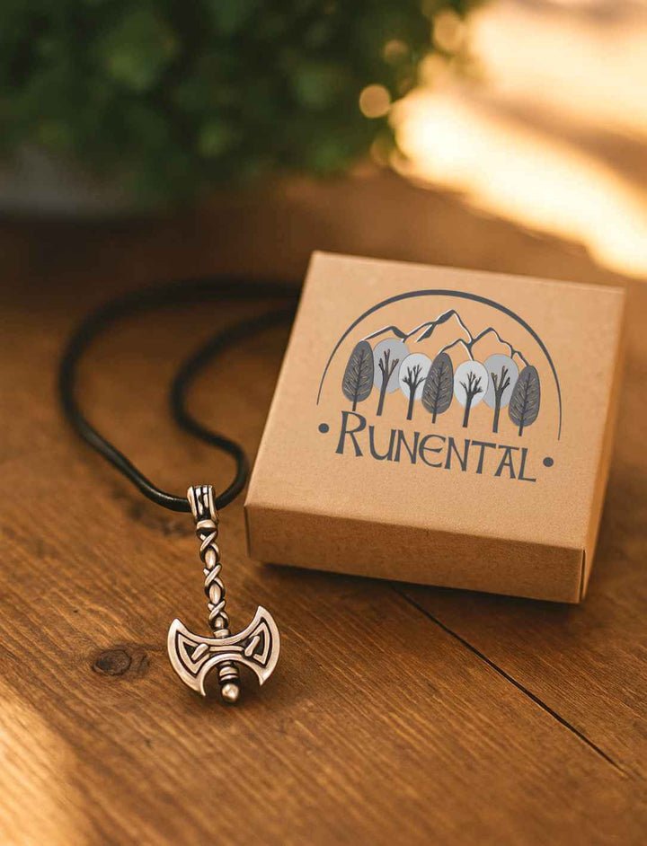 Amulett "Doppelklinge von Skarn" mit Axtsymbol auf Holztisch und Runental-Verpackung