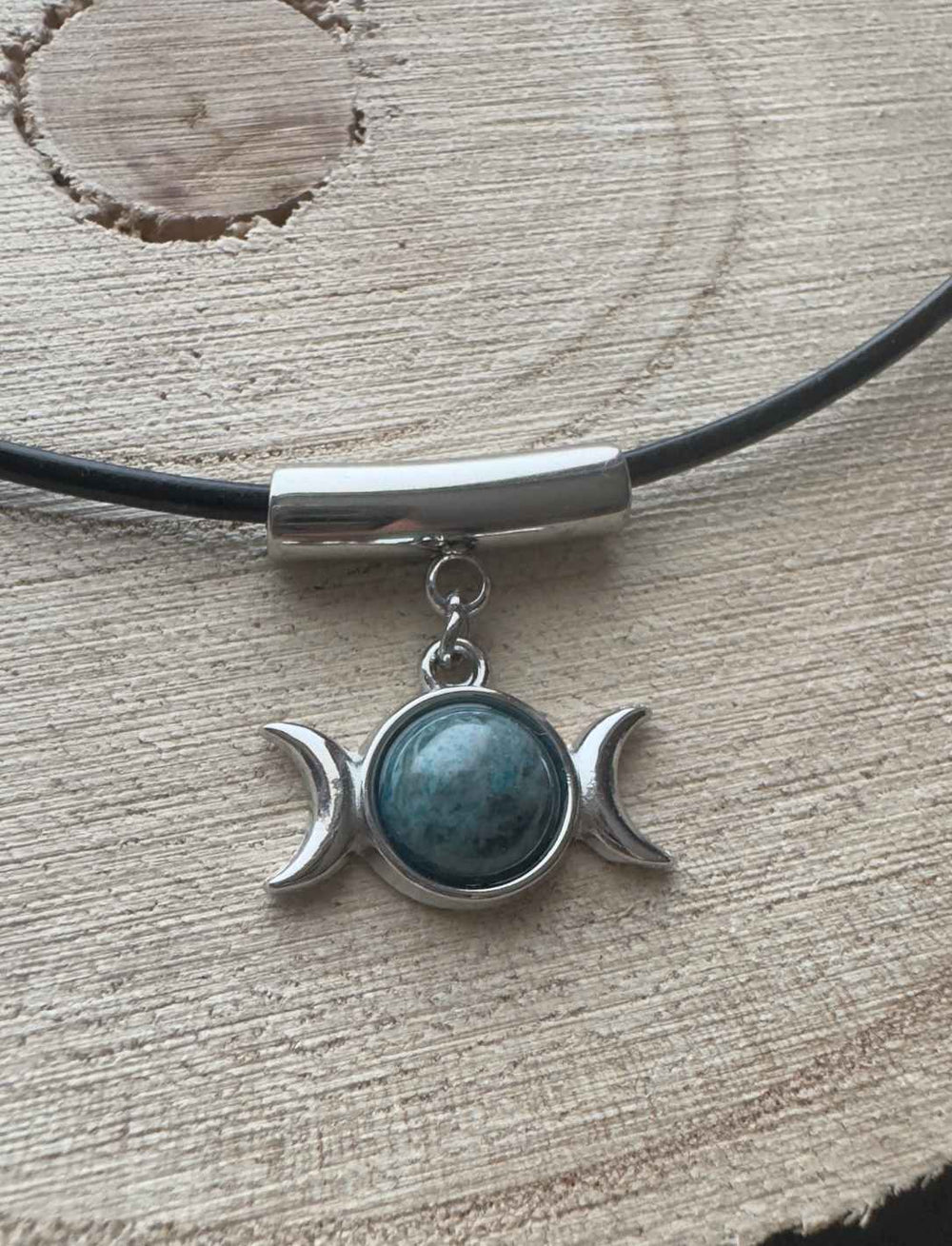 Dreimondzirkel Anhänger mit Apatit-Stein und Edelstahlfassung, fotografiert auf hellem Holzuntergrund