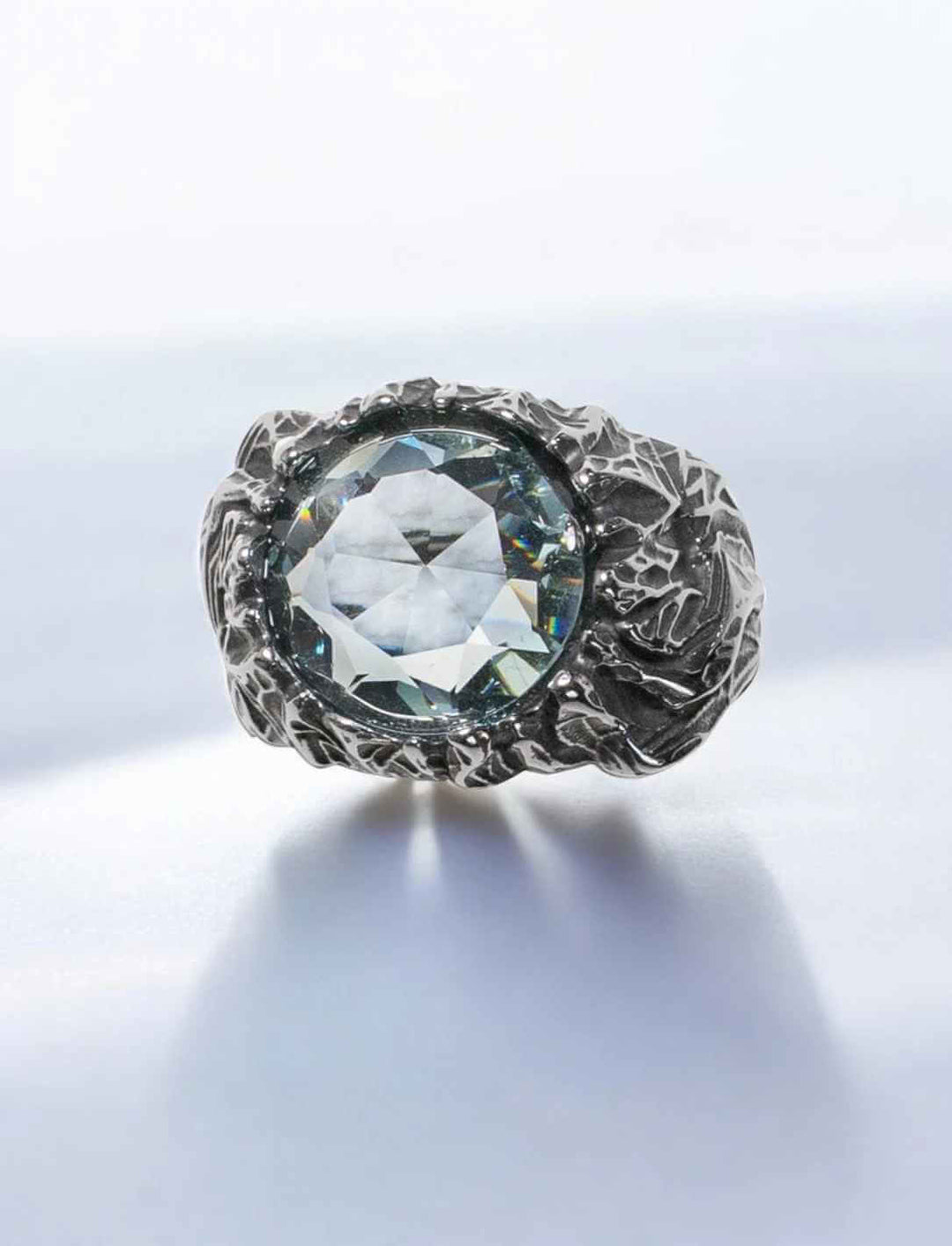 Mystischer Edelstahlring mit facettiertem eisblauen Stein – frontal fotografiert auf weißem Hintergrund.