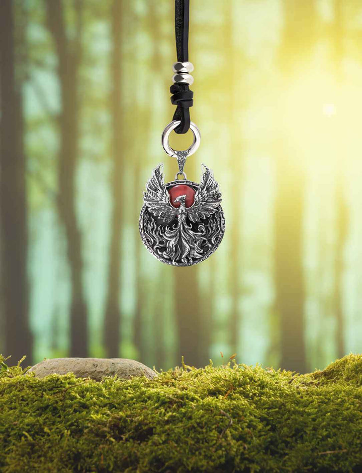 Feuerherz-Amulett mit Phönix schwebend im Waldlicht – mystisches Produktfoto mit Tiefenwirkung, mit Lederband des Waldläufers.