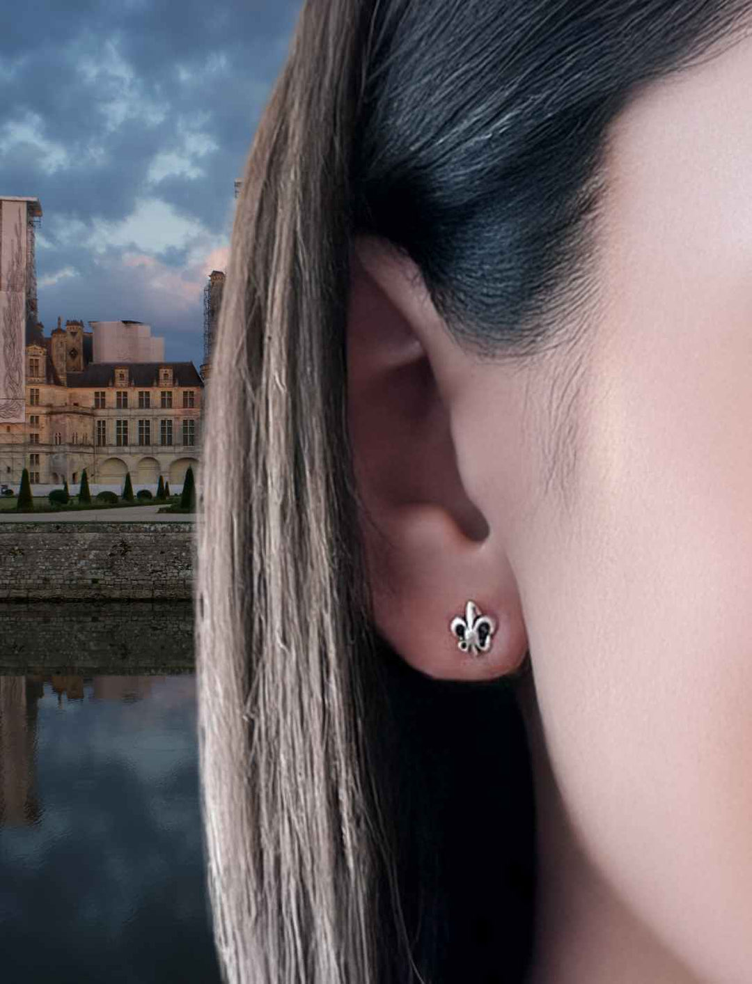 Frau trägt die Fleur de Lis Ohrstecker aus Silber vor einem französischen Schloss.