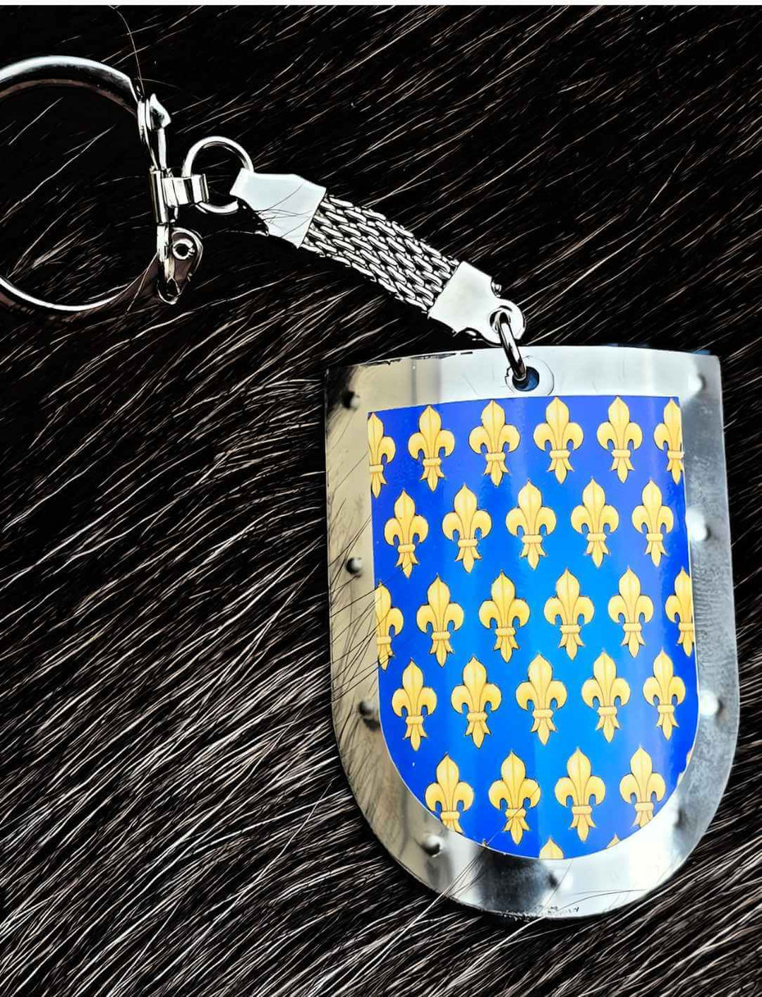 Exquisiter 'Fleur de Lis Schild' Schlüsselanhänger, platziert auf schwarzem Fell - eine Verbindung von Luxus und mittelalterlichem Flair, angeboten von Runental.de.