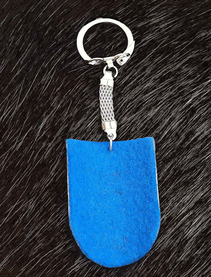 Die mit Filz überzogene Rückseite des 'Fleur de Lis Schild' Schlüsselanhängers, auf schwarzem Fell - ein Einblick in die feine Handarbeit aus dem Sortiment von Runental.de