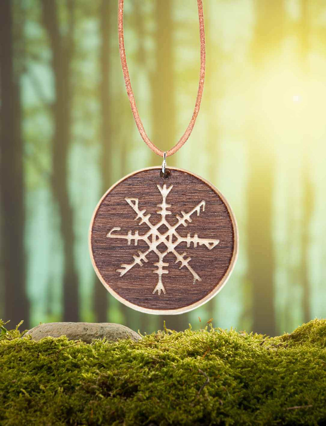 Futharkhelm Amulett aus Ahorn- und Nussbaumholz auf natürlichem Moos/Wald-Hintergrund.