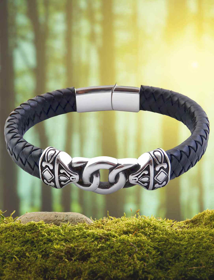 Geflochtenes Lederarmband mit Edelstahl-Gliedern, inspiriert von nordischer Mythologie, auf Moos im Wald liegend