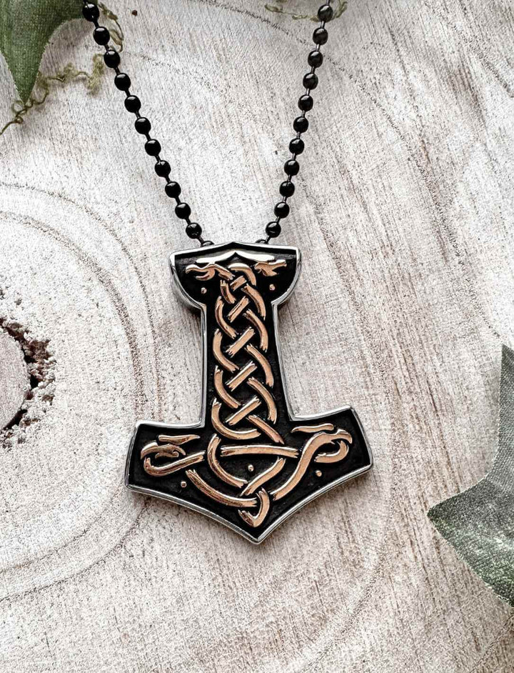 Hammer von Midgard – Zweifarbiger Thorhammer aus Edelstahl mit nordischem Muster auf Holzuntergrund fotografiert