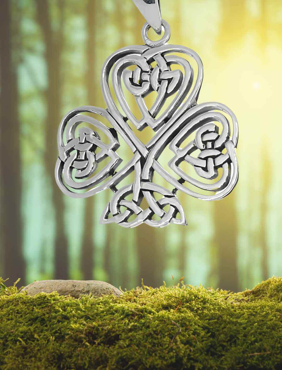 Silberanhänger Herzblatt von Éire – keltisches Kleeblatt in Naturkulisse auf Moos/Waldhintergrund.