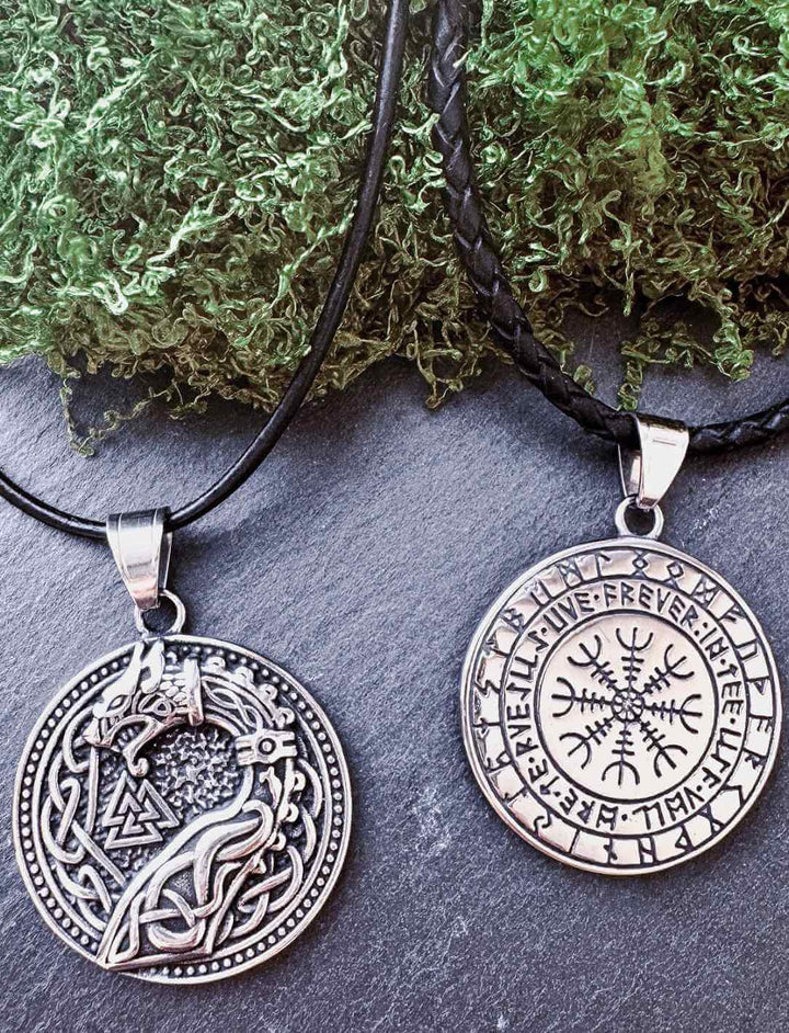 Jörmungandr Edelstahl-Anhänger mit Vorder- und Rückseite auf Lederkette, inszeniert mit natürlicher Kulisse – Symbol für Kraft, Richtung & Wandel