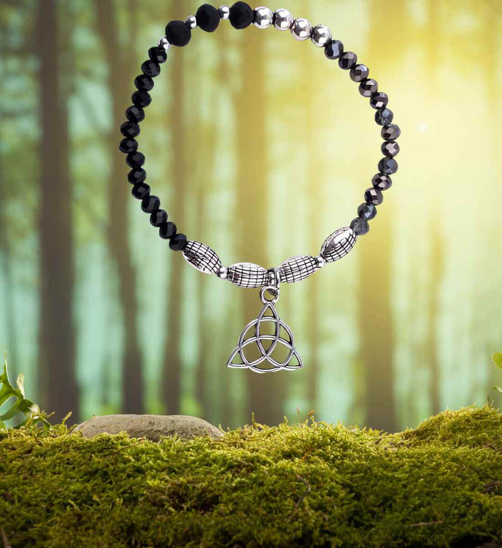 Armband des ewigen Knotens, präsentiert in seiner natürlichen Pracht auf einem Moos- und Waldhintergrund, symbolisiert die tiefe Verbindung zur Erde.