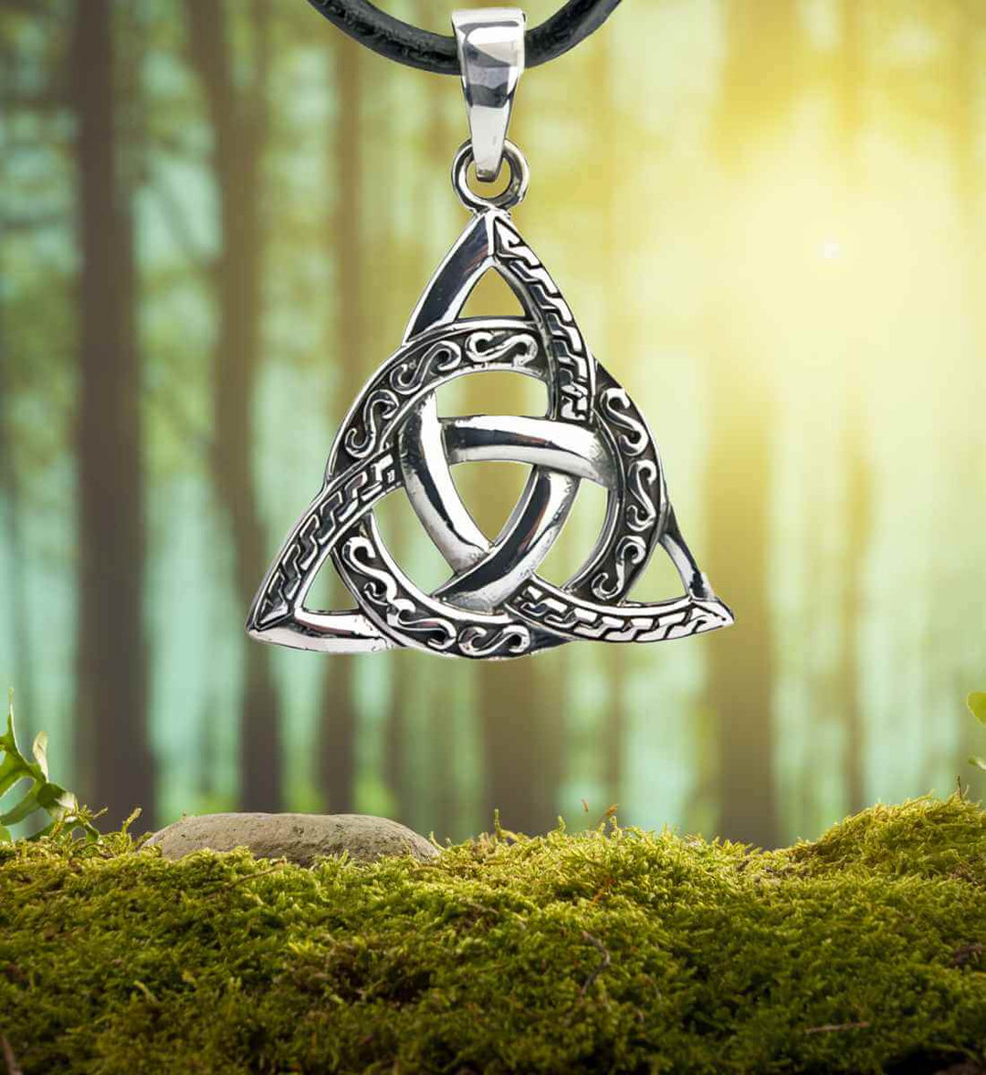 Knoten der Unendlichkeit aus 925 Sterling Silber, kunstvoll drapiert auf einem moosbedeckten Waldhintergrund.