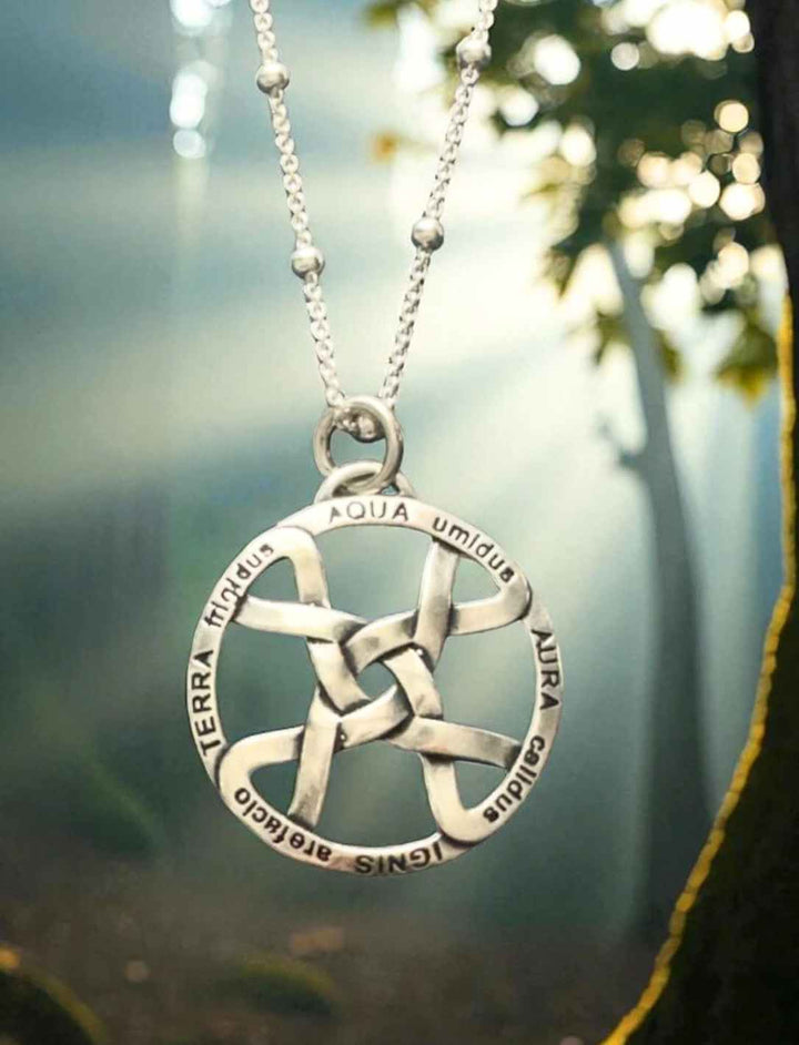 Silbernes Elemente-Amulett mit lateinischer Gravur, aufgenommen mit Kette im natürlichen Waldhintergrund.