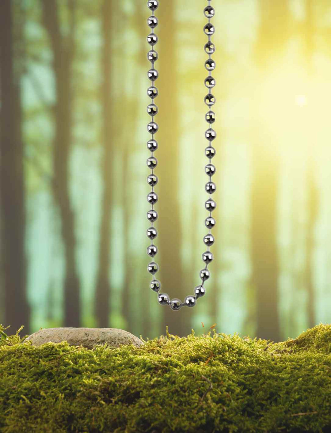 Kugelkette der alten Legenden aus Edelstahl, präsentiert auf Moos und in einer mystischen Waldkulisse, symbolisiert Stärke und Eleganz.