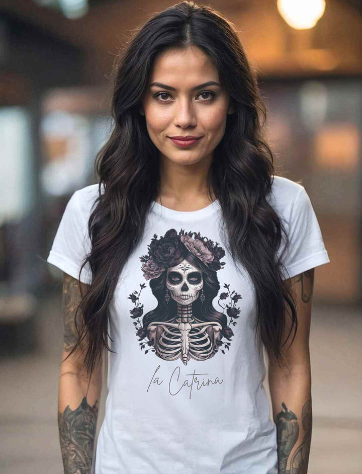 Junge Frau mit dunklem Haar trägt das “Catrina Deluxe” Damen T-Shirt in Weiss – Mystisches Design inspiriert vom Día de los Muertos, fotografiert in einer urbanen Umgebung.
