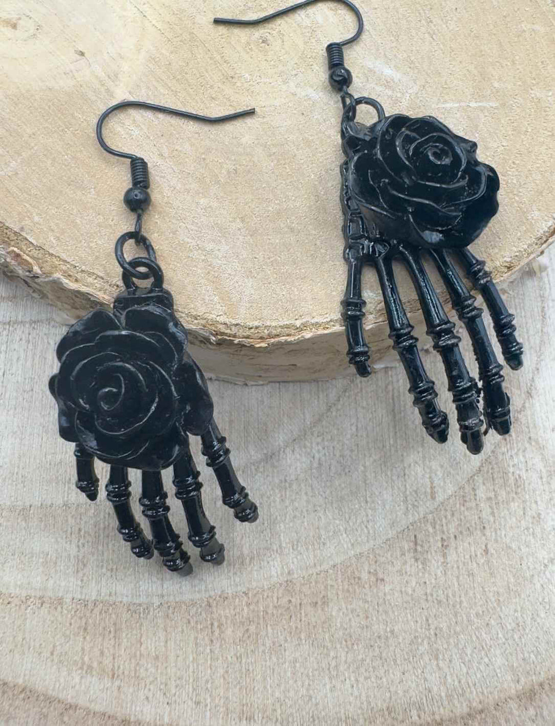 Schwarze Skelett-Ohrringe „La Rosa Oscura“ aus der Runental Kollektion – schwarze Rose auf filigraner Skeletthand, inspiriert von La Catrina, fotografiert auf hellem Holz