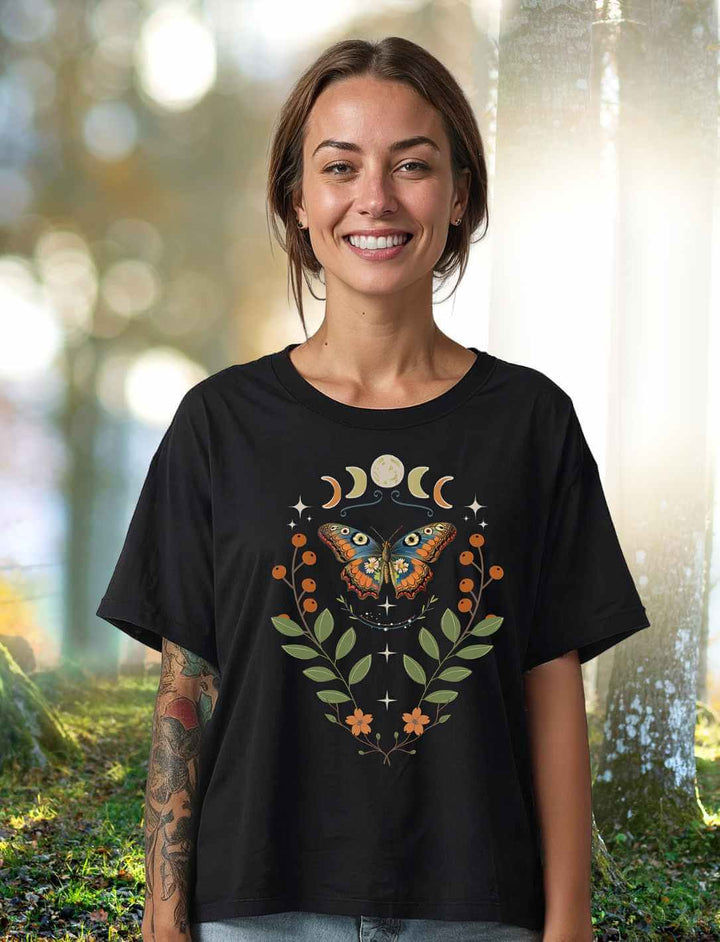 Model trägt das Relaxed Fit Damen T-Shirt „Lunaflora – Magischer Wandel“ in Schwarz – mit mystischem Schmetterlingsmotiv, Mondsymbolen und floralen Elementen.