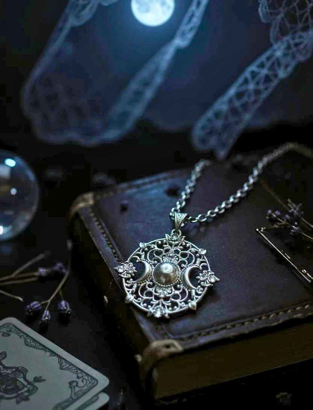 Mystischer Anhänger „Lunaria Noctis“ mit Triple-Moon-Symbol auf antikem Tisch bei Kerzenschein – 925 Silber an 45 cm Ringgeflechtkette