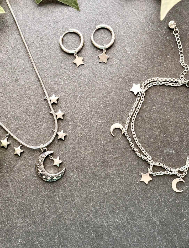SET: Lunaria Edelstahlkette mit Mond & Sternen – Fantasy Schmuck auf grauem Stein mit Blättern fotografiert. Bestehend aus Halskette, Fusskettchen und Creolen.