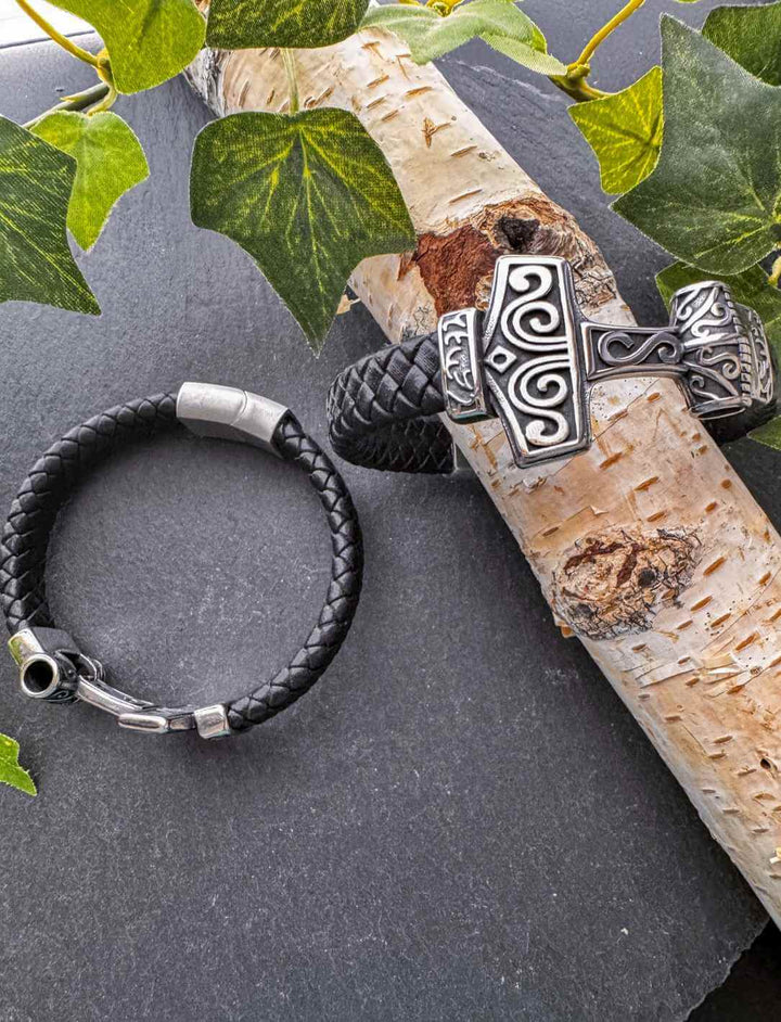 Mjölnirs Griff – nordisches Lederarmband mit Edelstahl und Magnetverschluss, flach ausgelegt neben Thorshammer auf Birkenast.