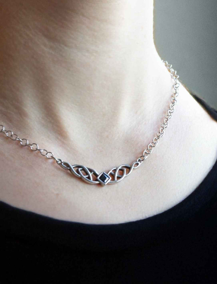 Nahaufnahme des Anhängers der Nocturna-Kette mit filigraner keltischer Gravur und dunklem Zirkonia an einem Frauenhals angeleggt.