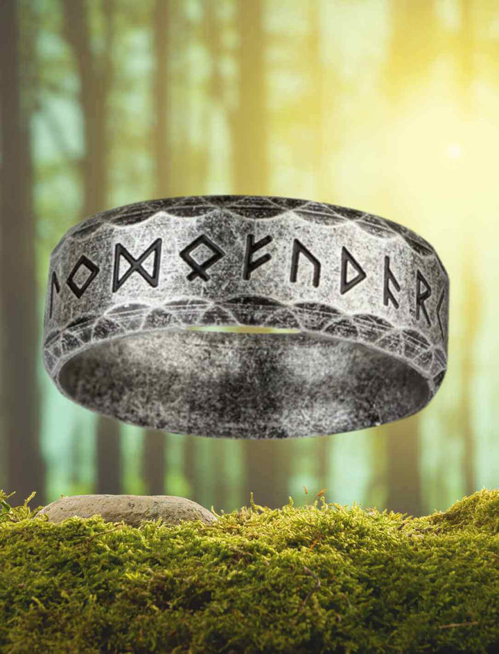 Ring der alten Kräfte aus Edelstahl, verziert mit Runenalphabet, in antiker Optik auf Moos präsentiert.