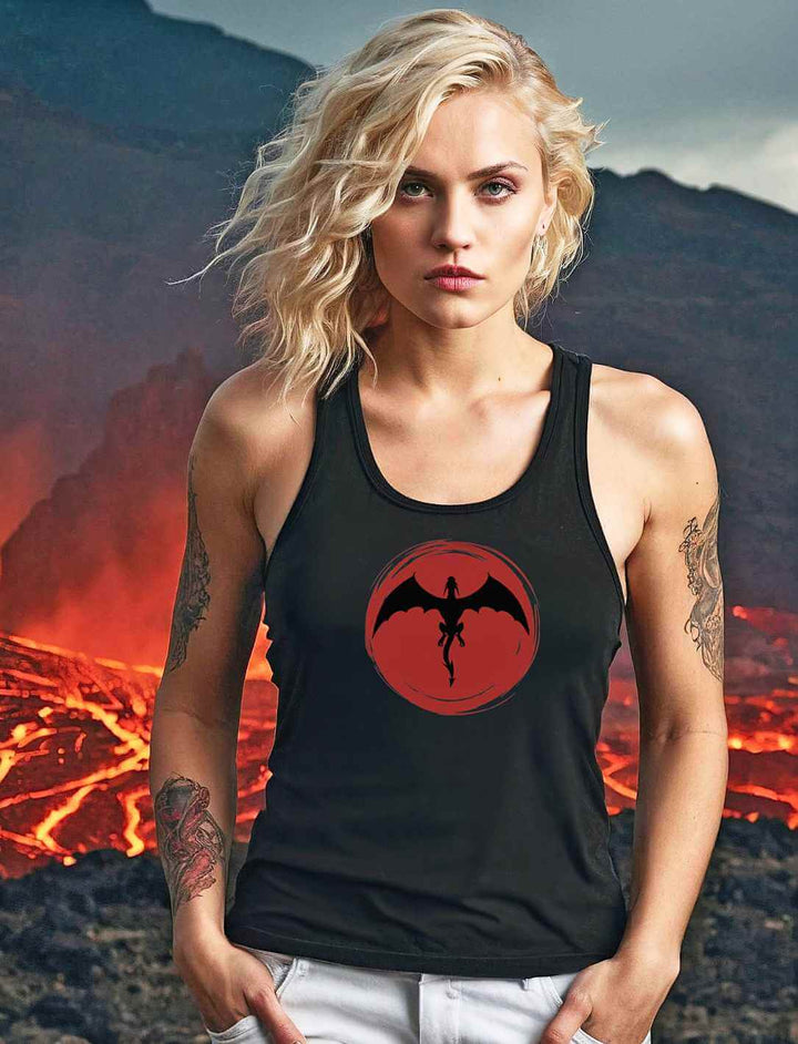 Blonde junge Frau in 'Saga of the Dragon' Tank Top in Schwarz, umgeben von einer lebendigen Lavalandschaft, die die Macht und Energie des Drachenmotivs unterstreicht.