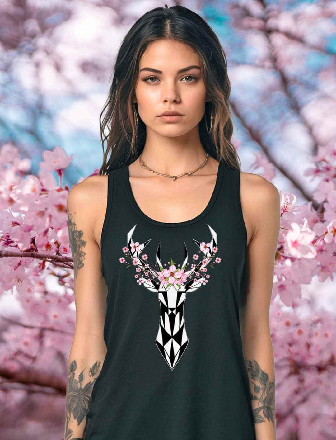 Junge Frau in einem schwarzen Sakura Deer Organic Damen Tank Top, verziert mit einem Hirsch- und Sakura-Blüten-Design, vor einem Hintergrund aus blühenden Kirschblüten