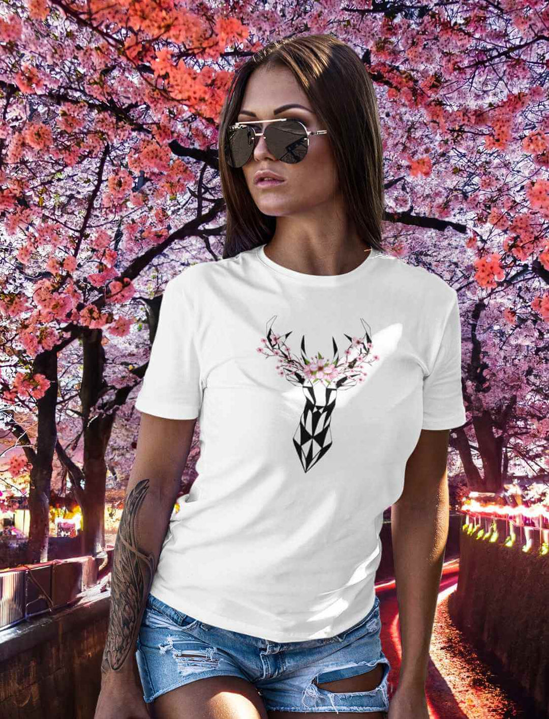 Eine junge Frau prĂ€sentiert das "Sakura Deer" T-Shirt in WeiĂ, dessen Design mit Hirsch und Sakura-BlĂŒten die Eleganz und Schlichtheit der japanischen Ăsthetik betont.