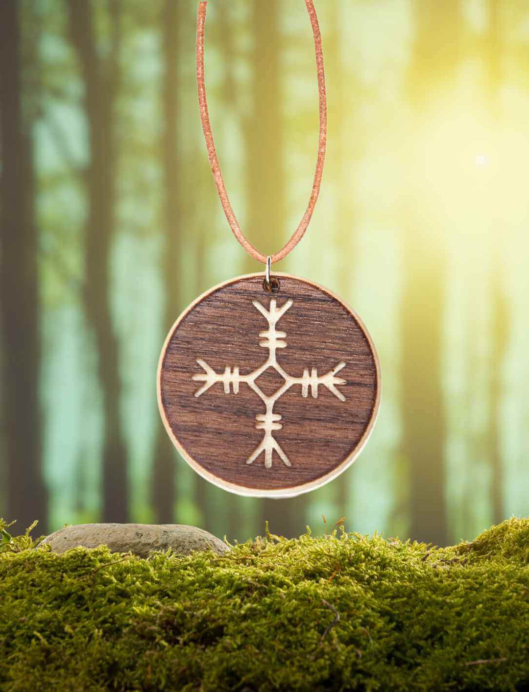 Schreckenshelm Amulett aus Ahorn- und Nussbaumholz auf natürlichem Moos/Wald-Hintergrund.