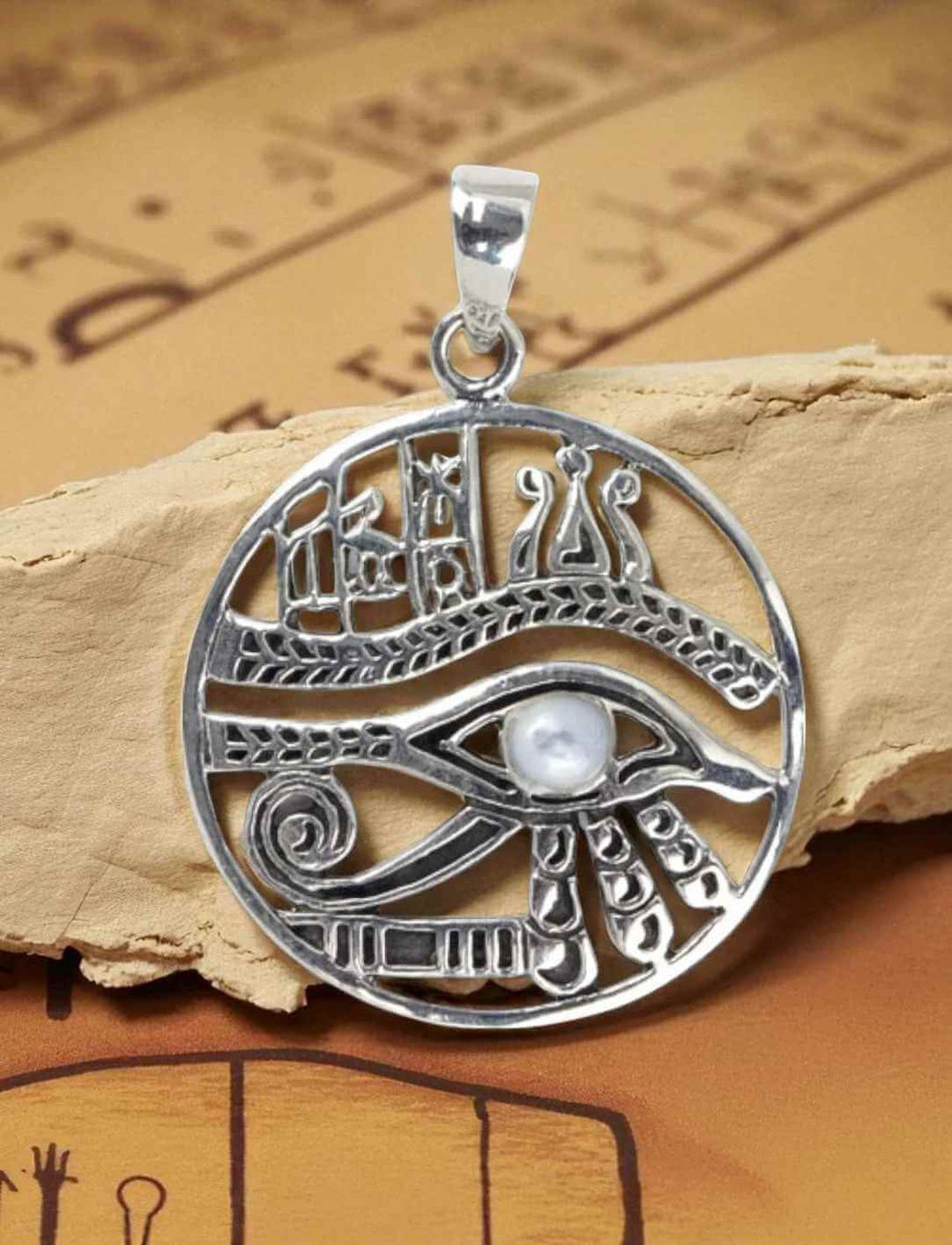 Silberanhänger Auge des Horus mit Mondstein auf antikem Papyrus-Hintergrund fotografiert