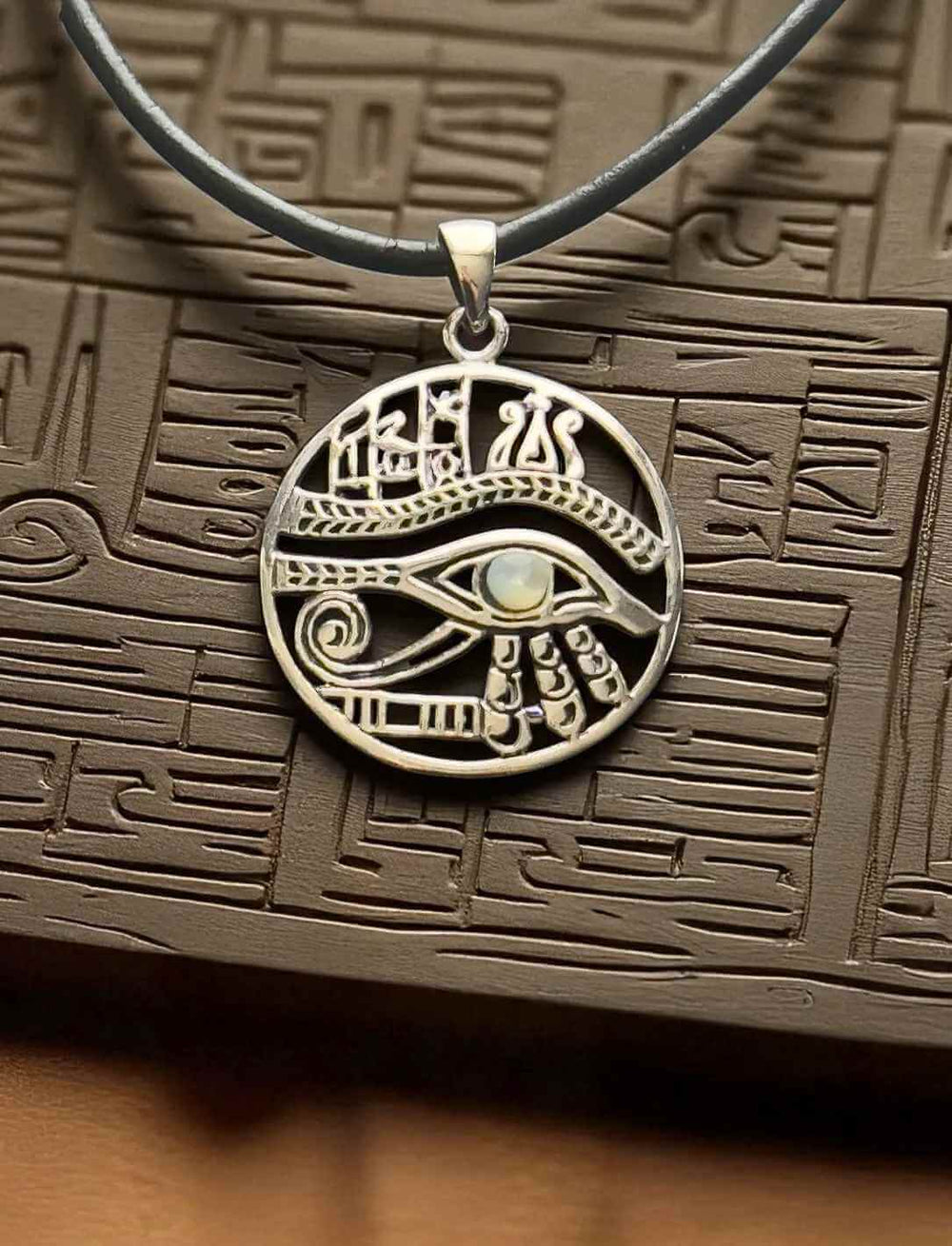 Amulett Auge des Horus aus 925er Silber mit Lederkette auf dunkelbraunem, altägyptischem Relief