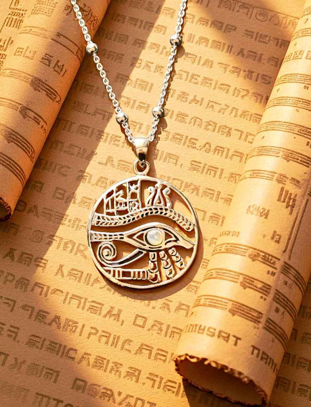 Silberanhänger mit Auge des Horus und Mondstein auf ägyptischer Schriftrolle in warmem Licht