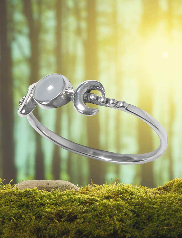 Silberring mit Mondstein und Mondphasen-Design auf Moos im mystischen Licht