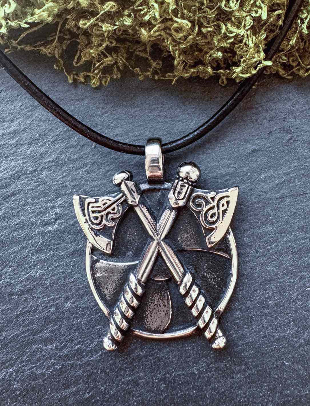 Detailreicher Edelstahl-Anhänger „Skjaldborg“ mit gekreuzten Äxten und Rundschild, präsentiert auf Lederkette – Symbol für Schutz und Zusammenhalt.
