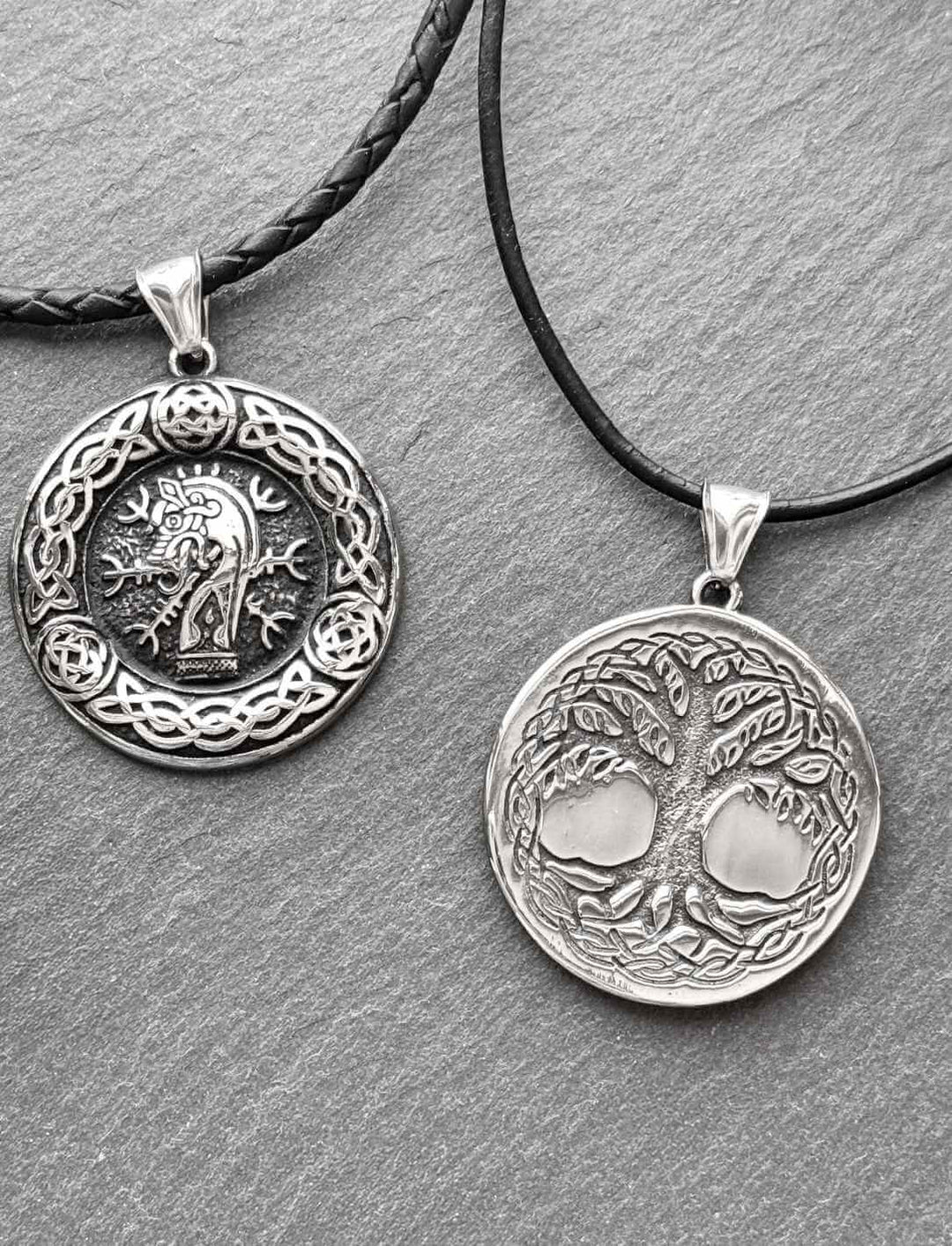 Doppelseitiger Anhänger aus Edelstahl mit Sleipnir und Yggdrasil, inspiriert von der nordischen Mythologie – präsentiert an Lederketten auf Steinplatte