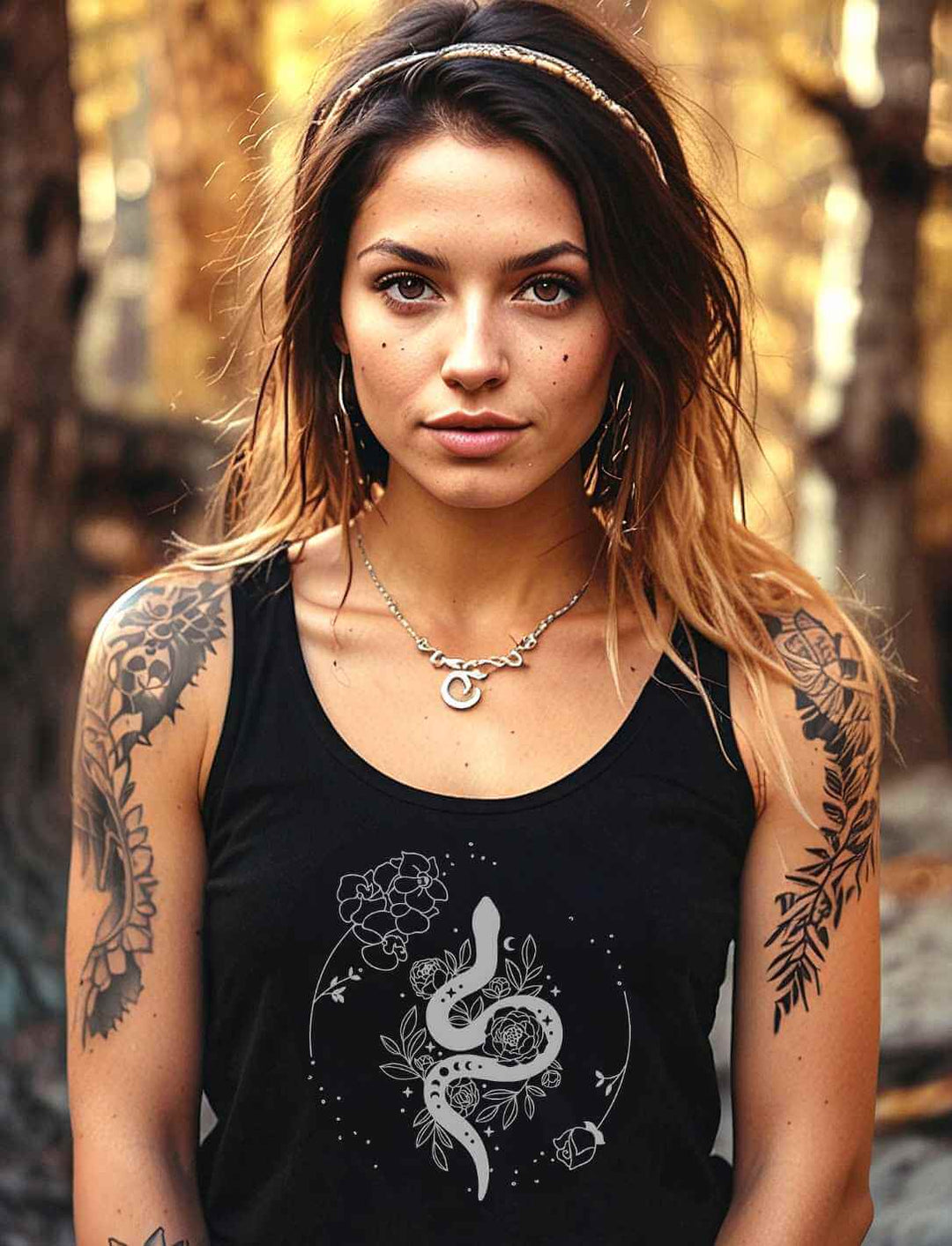 Junge Frau trägt das 'Snake of Wisdom' Damen Tanktop in Schwarz, das mit einem weißen Schlangen- und Blumenmuster bedruckt ist, vor einem üppigen grünen Gartenhintergrund, der die Verbindung zur Natur unterstreicht